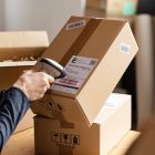 Hands of young woman scanning barcode on delivery parcel. Worker scan barcode of cardboard packages before delivery at storage. Woman working in factory warehouse reading and scanning labels on the boxes with bluetooth barcode scanner.